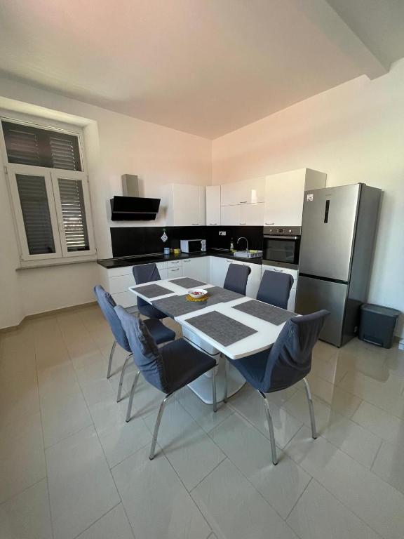 a kitchen with a table and chairs and a refrigerator at Barbabianca Apartment in Koper