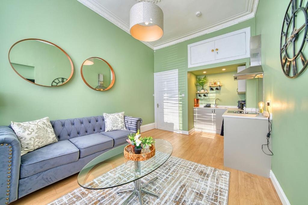 ein Wohnzimmer mit einem blauen Sofa und einem Glastisch in der Unterkunft 3-Bed Flat Free Parking 10 Mins to City Centre in Glasgow