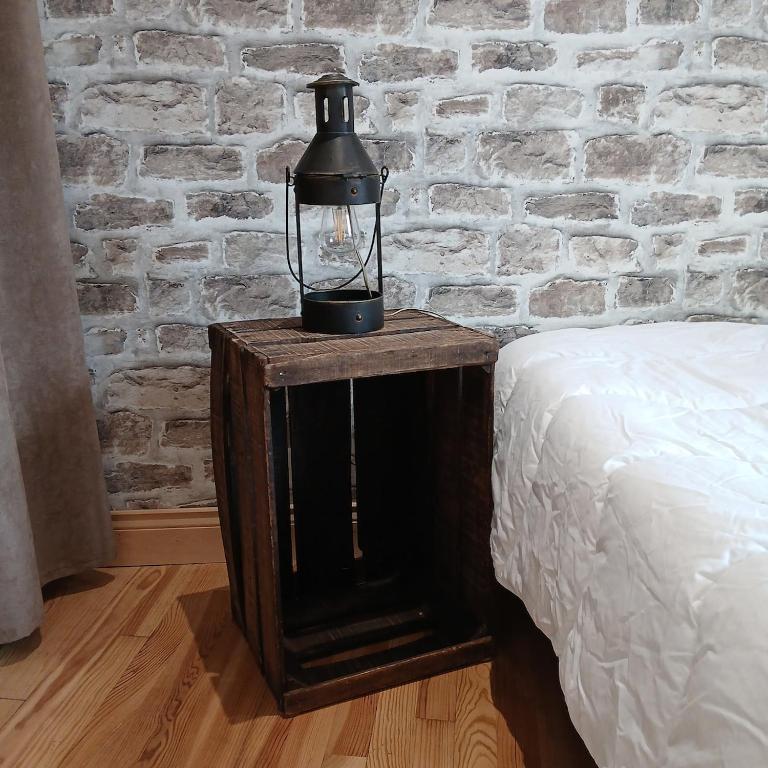 une lampe sur une table en bois à côté d'un lit dans l'établissement Maison calme et paisible, à Châteauneuf-les-Bains