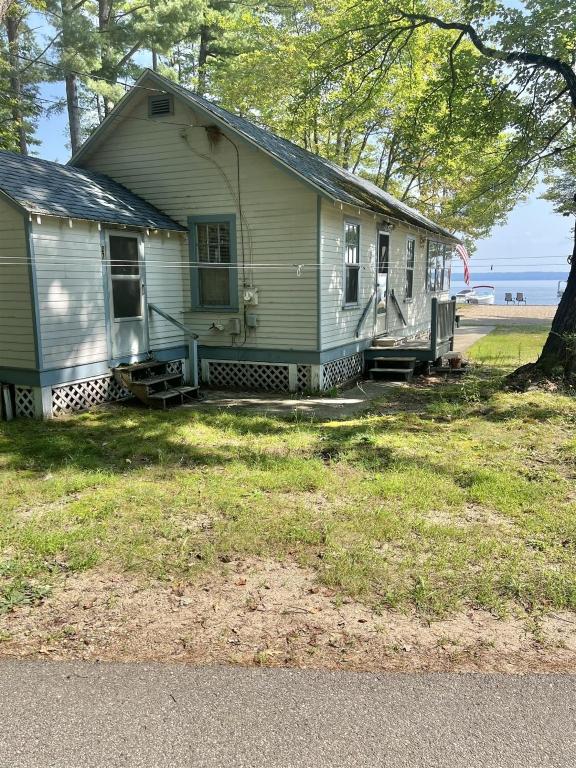 a white house with a porch and a tree at HARMON'S BEACH LIMIT 5 villa in Standish