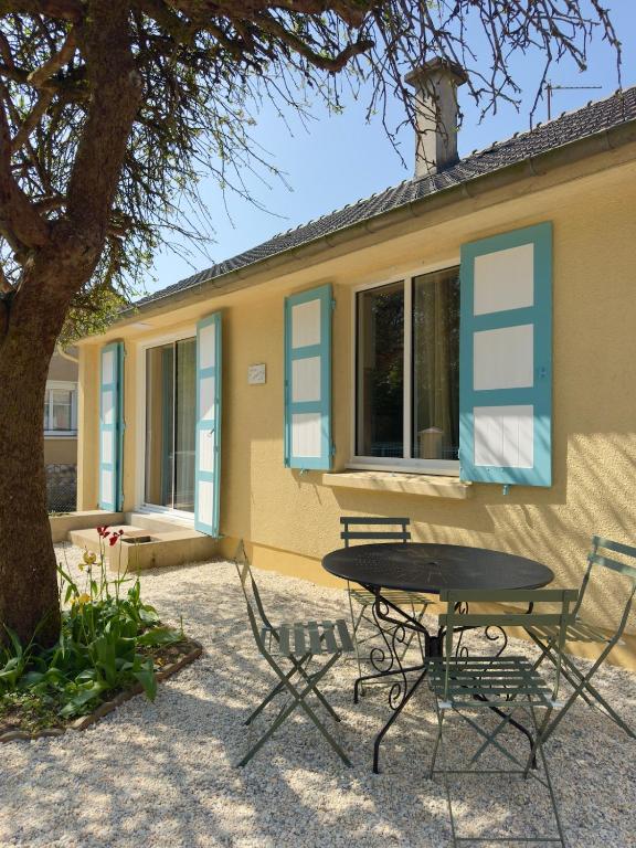 ein Tisch und Stühle vor einem Haus in der Unterkunft Villa Cornelia Bagnoles Mezzanine Confort & Nature in Bagnoles de l'Orne