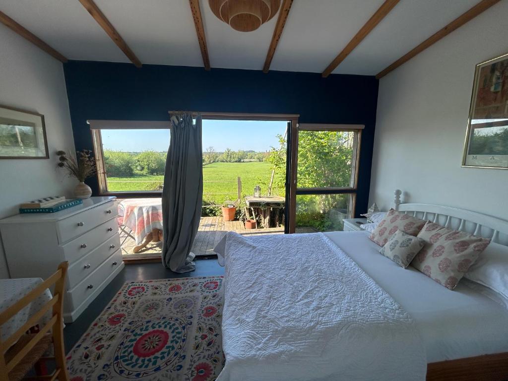 a bedroom with a bed and a large window at Countryside Garden Summer House in Calne