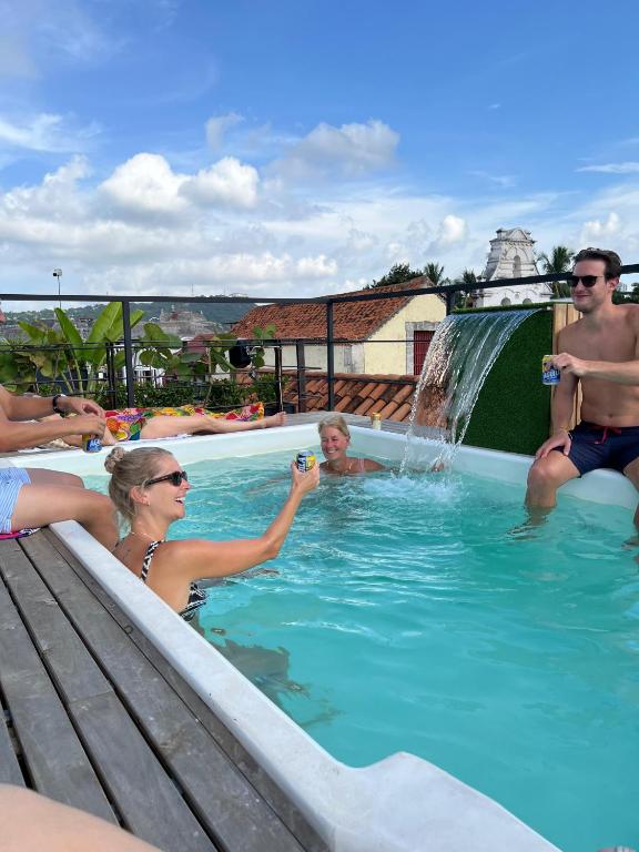 a group of people in a swimming pool with a waterfall at Casa Helena Getsemaní in Cartagena de Indias