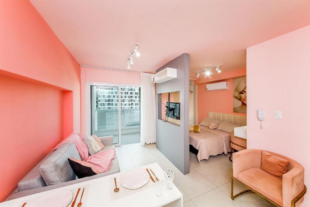 a room with pink walls and a living room with a couch at Studio Pink com ar, varanda, academia e piscina in Juiz de Fora