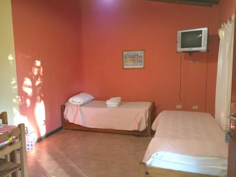ein Zimmer mit zwei Betten und einem Fernseher an der Wand in der Unterkunft Bungalows Génesis ideal para las familias a 12 cuadras del parque termal in Federación