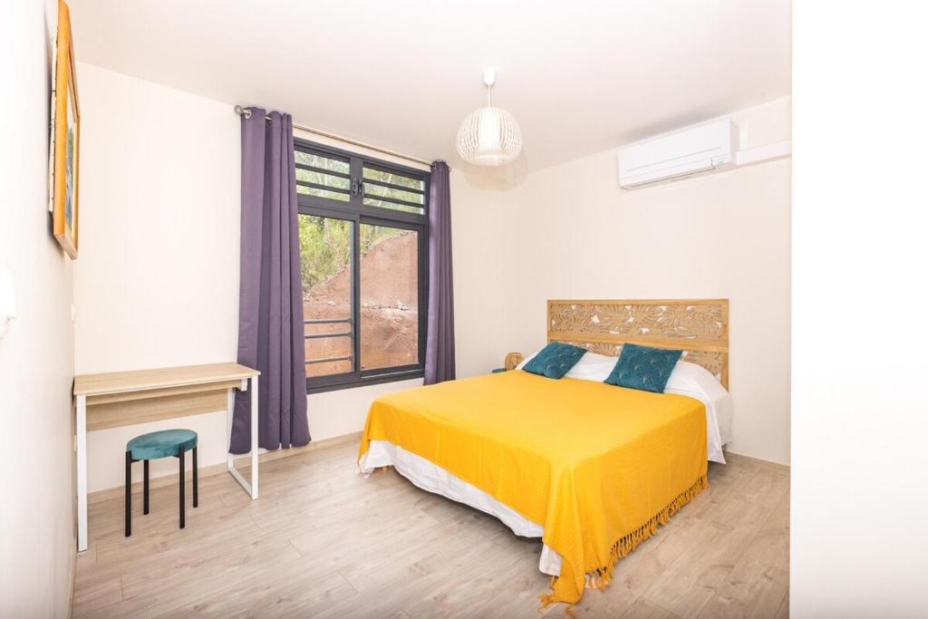 AvaeMaraea Deluxe Apt 2BR 2BA with Pool View near Tahiti Airport的一间卧室配有黄色的床和一张书桌