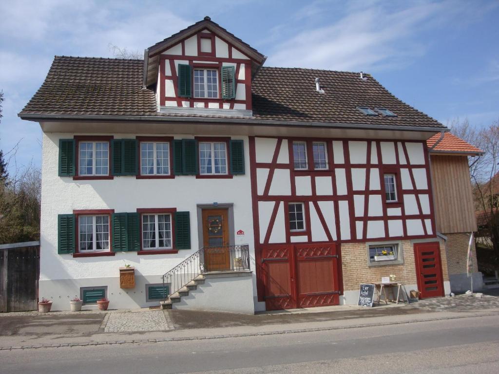 dom z czerwonymi drzwiami i zielonymi okiennicami w obiekcie Bed and Breakfast Wegmann w mieście Andelfingen