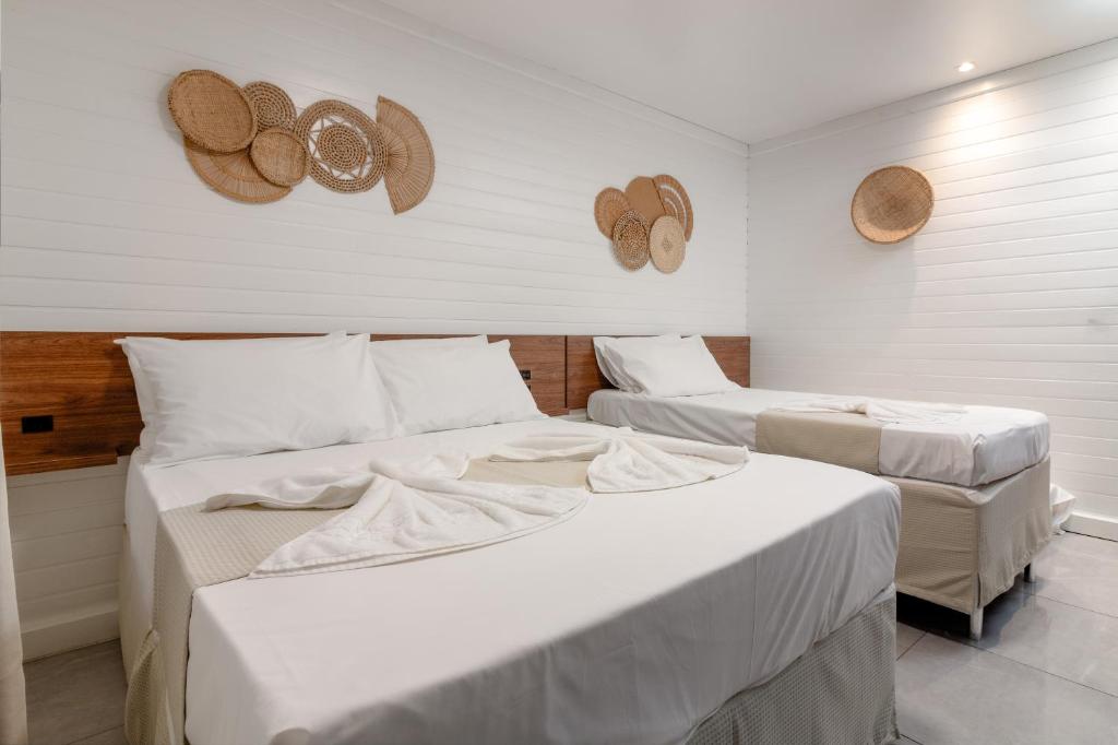 twee bedden in een kamer met hoeden aan de muur bij Ancoradouro Pousada in Penha