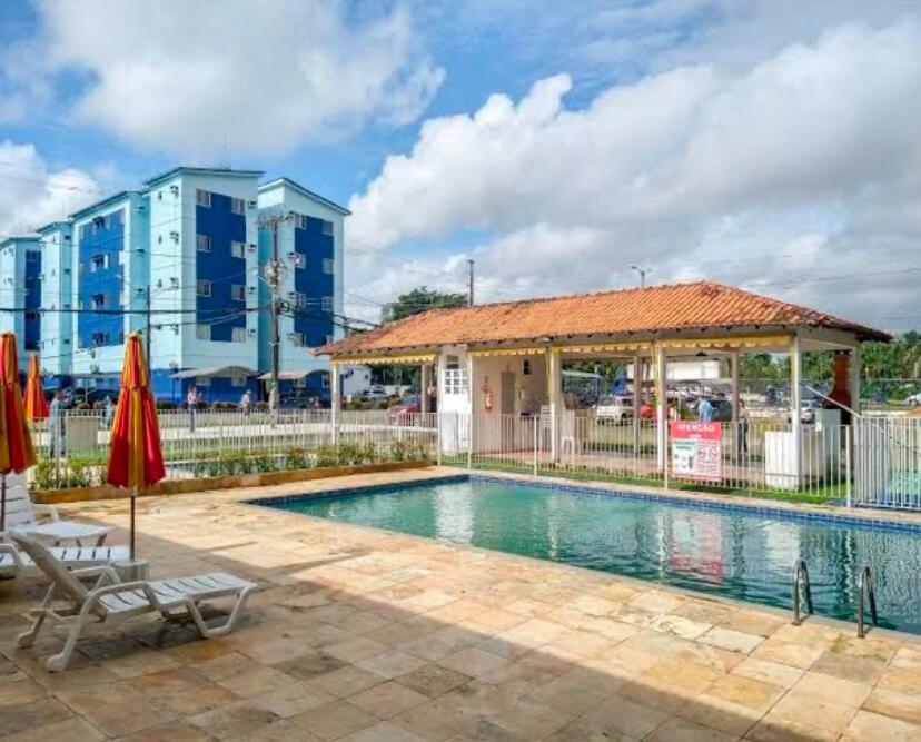 a swimming pool with a umbrella and a building at Alugo apartamento COP 30 in Ananindeua