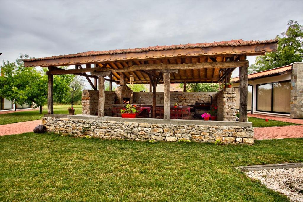 a wooden pergola on a stone wall in a yard at Holiday Homes Chudna in Breste