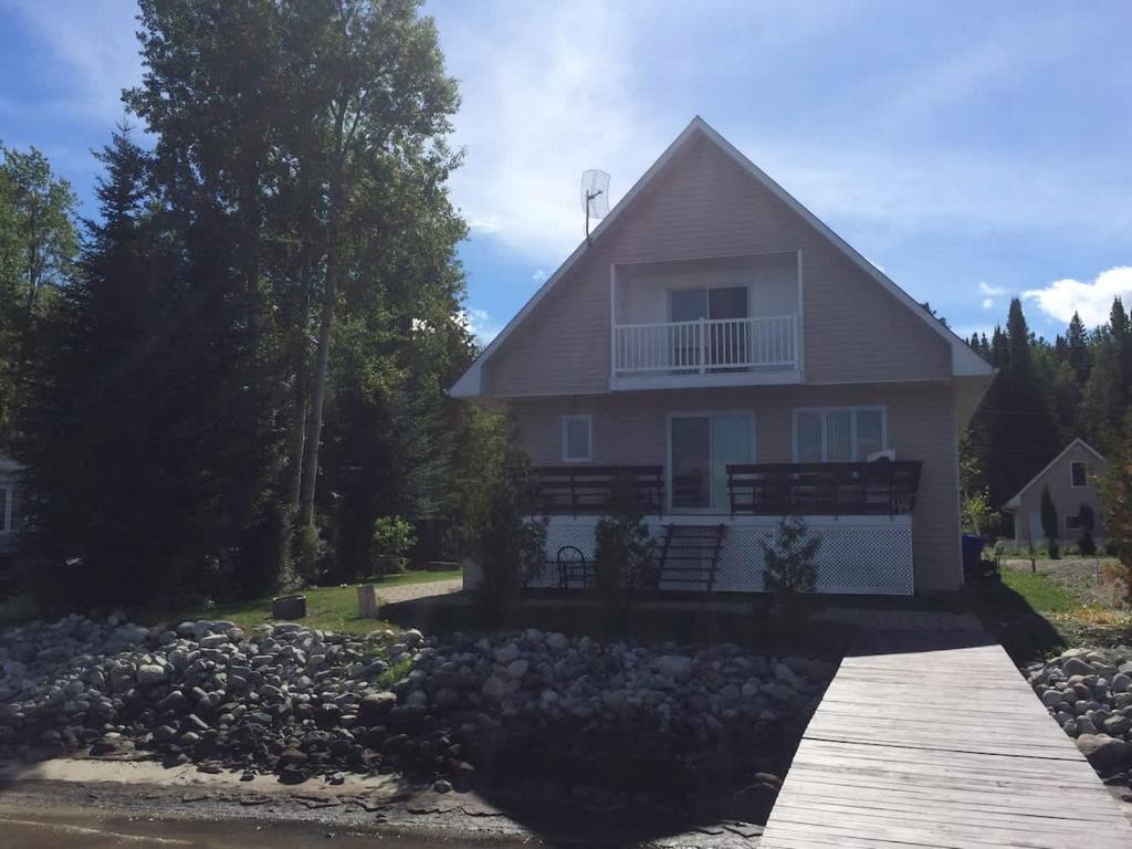 a white house with a porch and a wooden dock at Beautiful cottage on Lake Abitibi in Palmarolle
