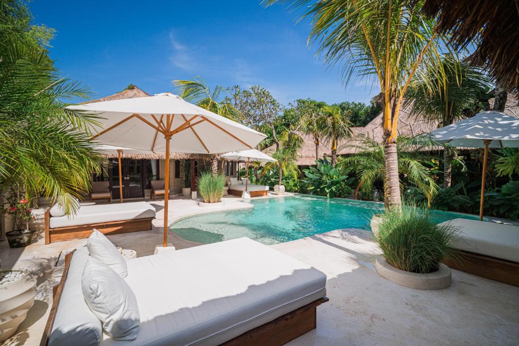 una piscina con sillas y sombrillas en un resort en Villa Coconut Heaven by Bali Villa Solutions, en Seminyak