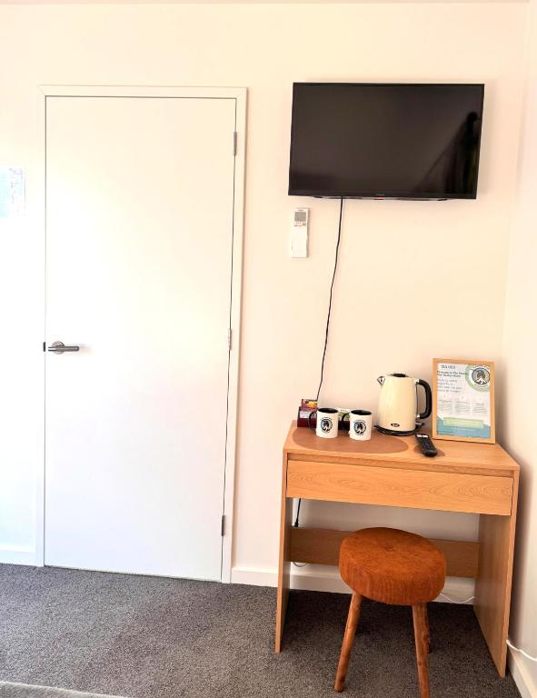 a room with a desk and a tv on a wall at The Flaming Kiwi Backpackers in Queenstown