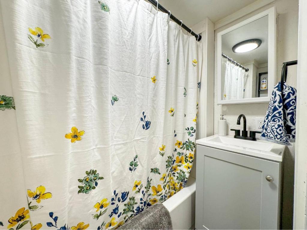 La salle de bains est pourvue d'un rideau de douche et de fleurs. dans l'établissement NEW - Mins to Manchester - Concord - River Views, à Hooksett