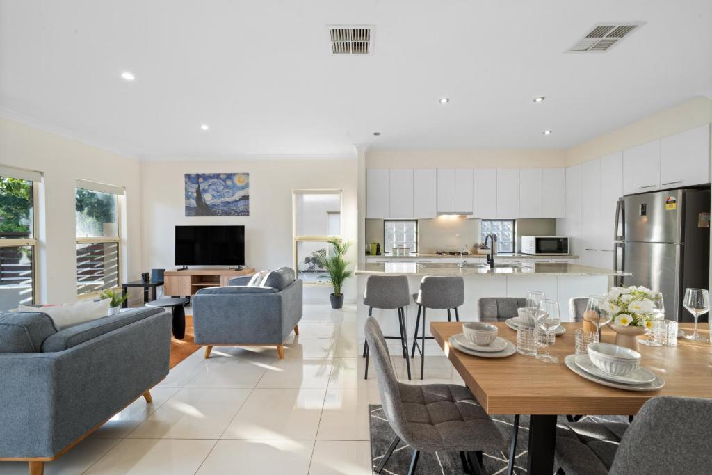 a kitchen and living room with a table and chairs at Fig & Fern - Modern Comfort between City & Coast in Glandore