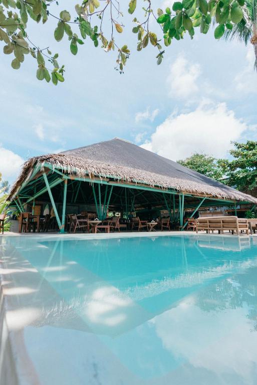 a resort with a thatched roof and a swimming pool at Bravo Beach Resort in General Luna