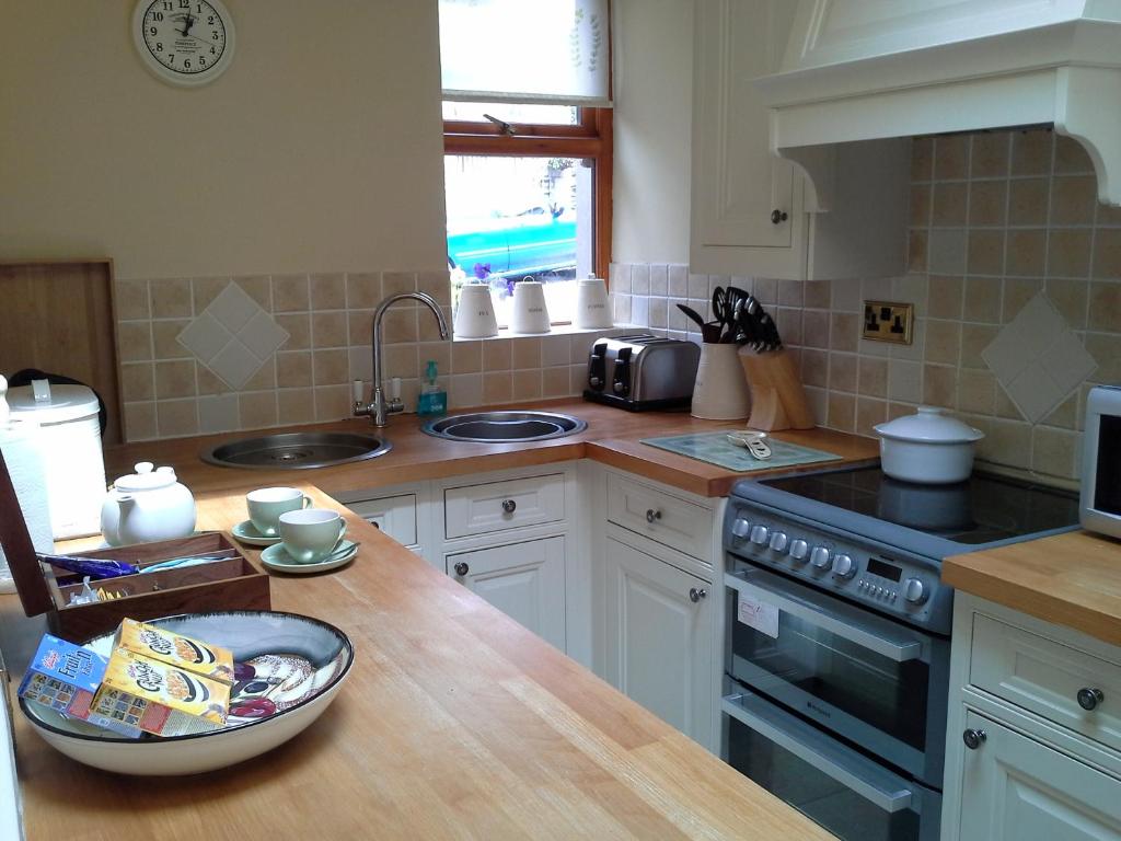 a kitchen with a counter with a sink and a stove at courtyard cottage in Kendal
