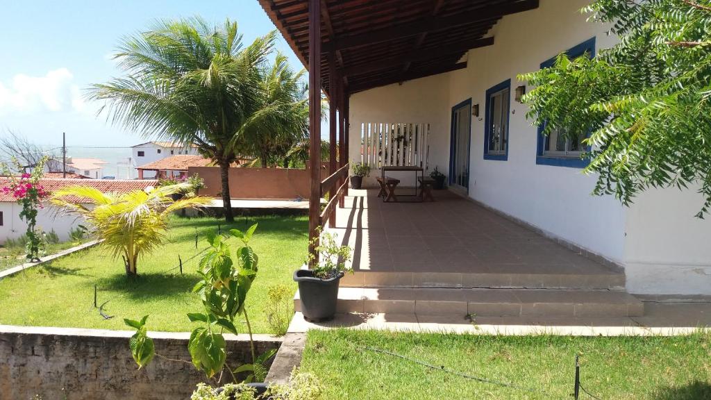 a house with a porch and a yard with palm trees at Natal Casa de Playa Coqueiros in Pitangui