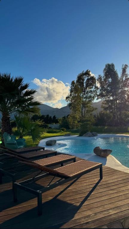- une piscine avec une terrasse en bois et de l'eau dans l'établissement VILLA luxueuse privée avec piscine lagon, à Calenzana