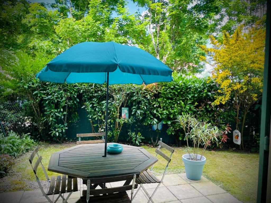 - une table de pique-nique avec un parasol bleu et des chaises dans l'établissement La Clef du Bonheur - 9 Min de Disney Jardin privatif, à Bailly-Romainvilliers