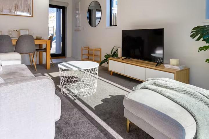 een woonkamer met een flatscreen-tv en een bank bij Stadium Suite on Southwark - Luxury in City Centre in Christchurch