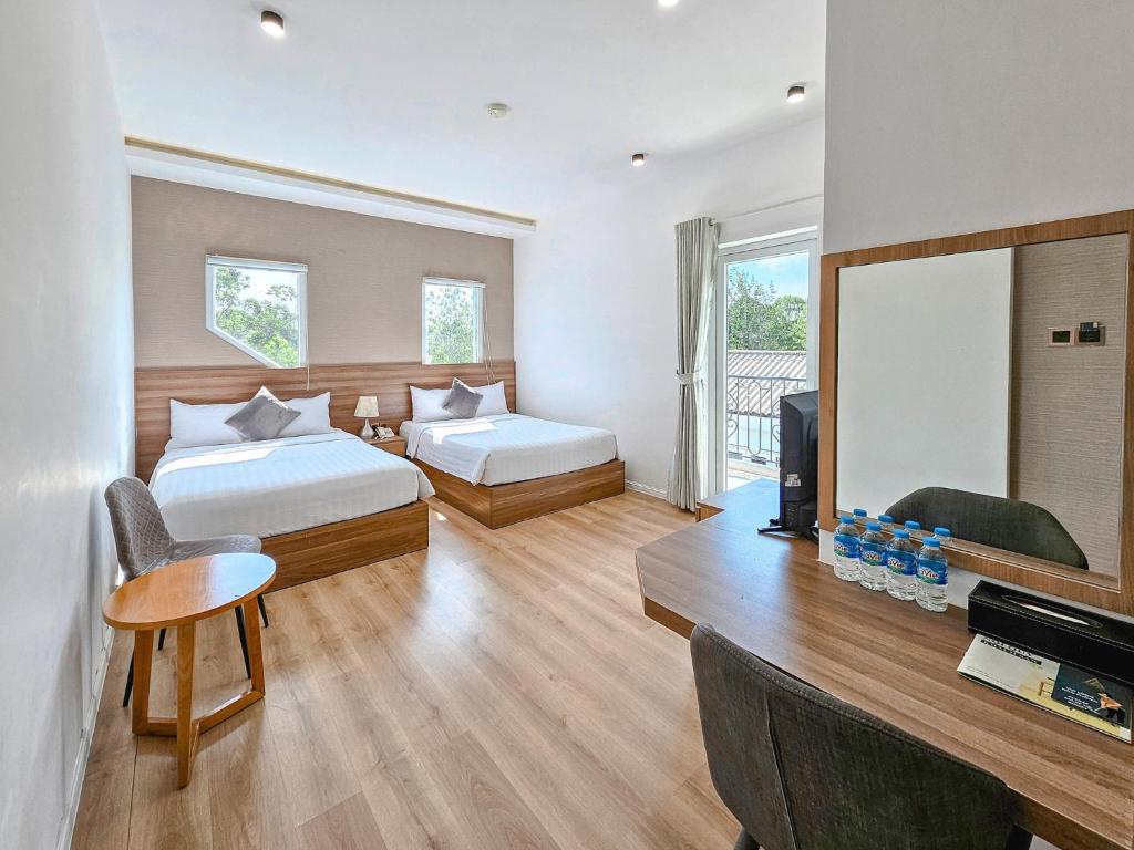 a hotel room with two beds and a television at NATURE LAND 2 - Song Anh Hotel Dalat in Da Lat