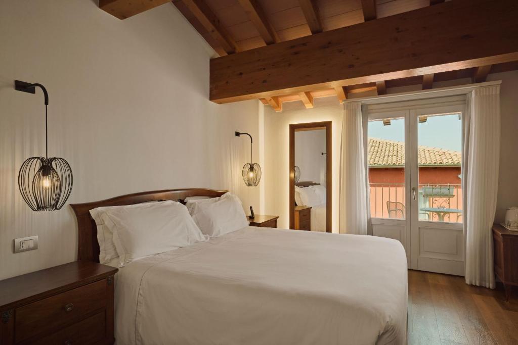 een slaapkamer met een groot wit bed en een raam bij Hotel Le Mura in Lazise