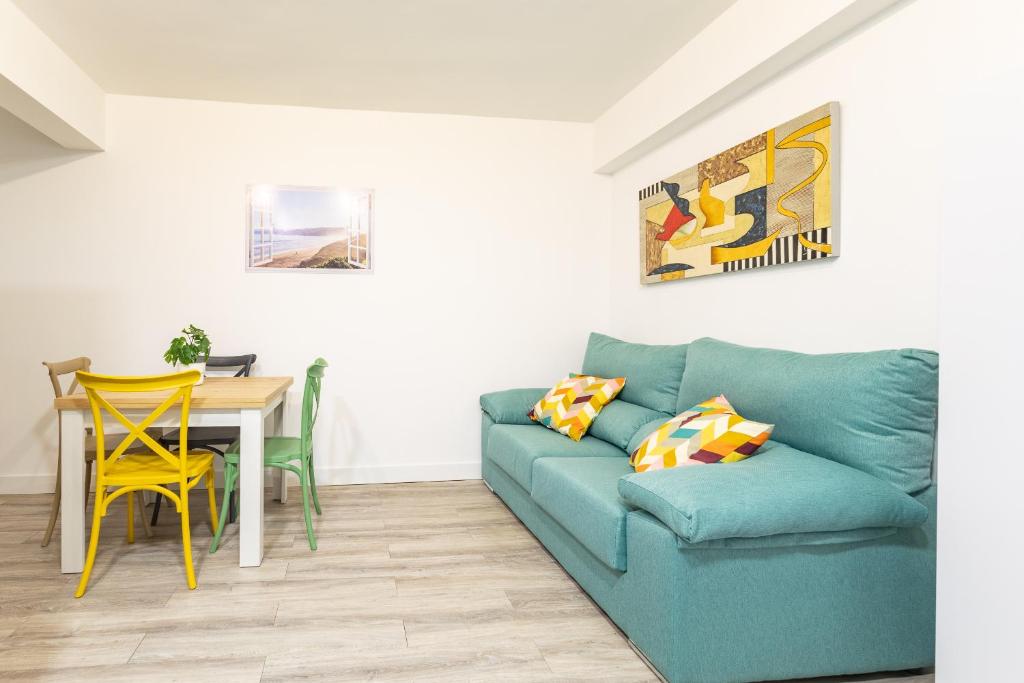 ein Wohnzimmer mit einem blauen Sofa und einem Tisch in der Unterkunft Súpercéntrico Santander in Santander
