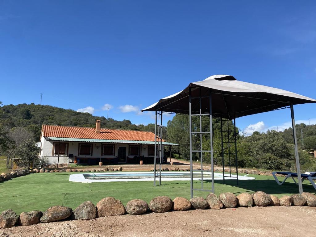 - une piscine avec un parasol en face d'une maison dans l'établissement Las Chorreras del Orejón 1, à Villaviciosa de Córdoba
