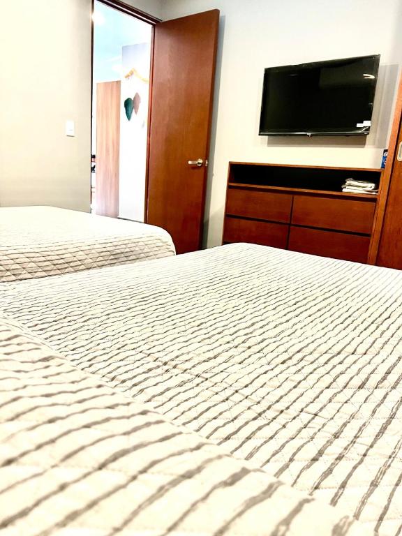 a bedroom with two beds and a flat screen tv at Luxury 2bdr Apt with Direct Pool in Paramar Black in Tulum