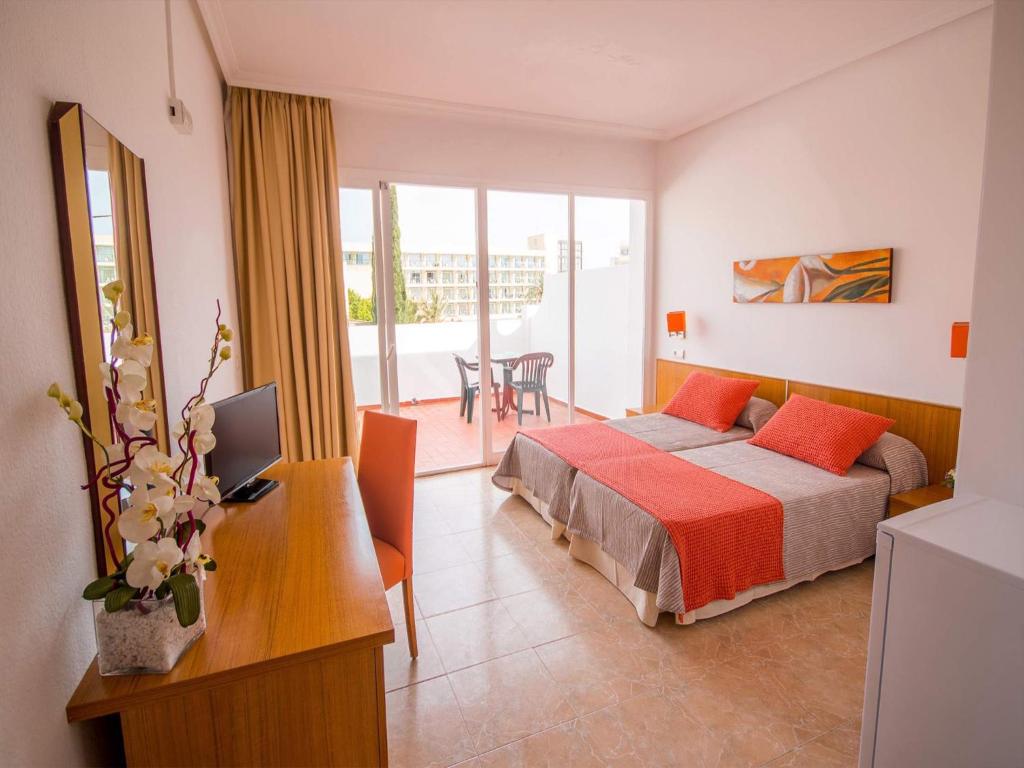 a bedroom with a bed and a desk with a computer at Hostal Los Pinos in Es Cana