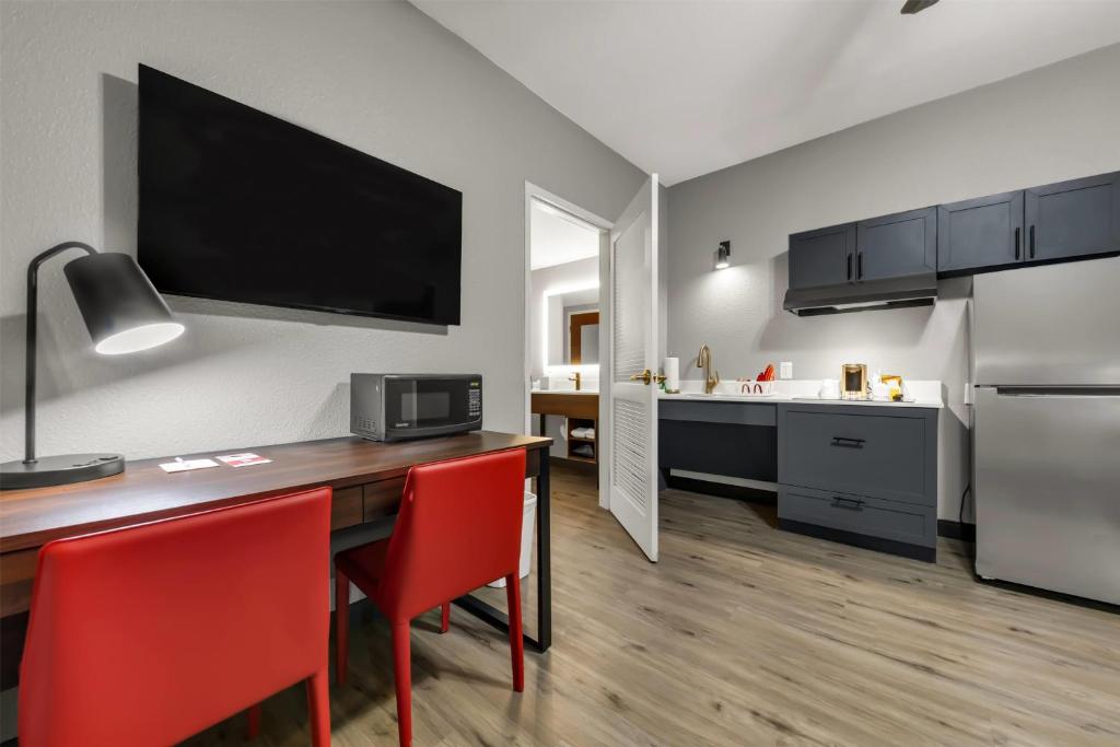 a kitchen and dining room with a table and red chairs at Hawthorn Extended Stay by Wyndham College Station in College Station