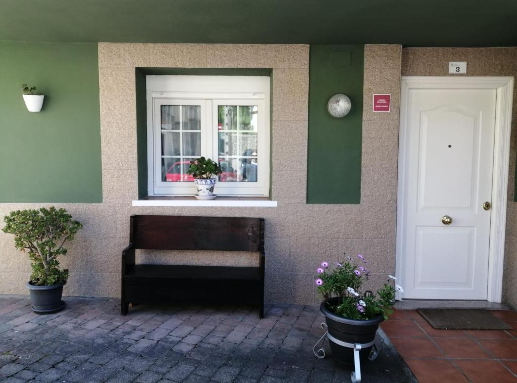 a house with a bench and a window and plants at Vegalmar in Limpias