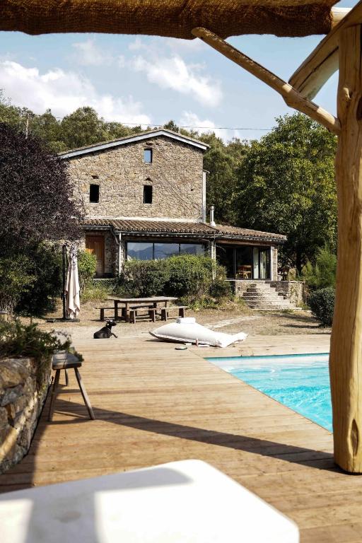 une maison en pierre avec une piscine en face de celle-ci dans l'établissement Le petit paradis cévenol - piscine & salle de sport, à Notre-Dame-de-la-Rouvière