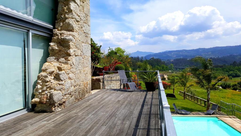 a house with a wooden deck and a swimming pool at Quinta de Padreiro in Arcos de Valdevez