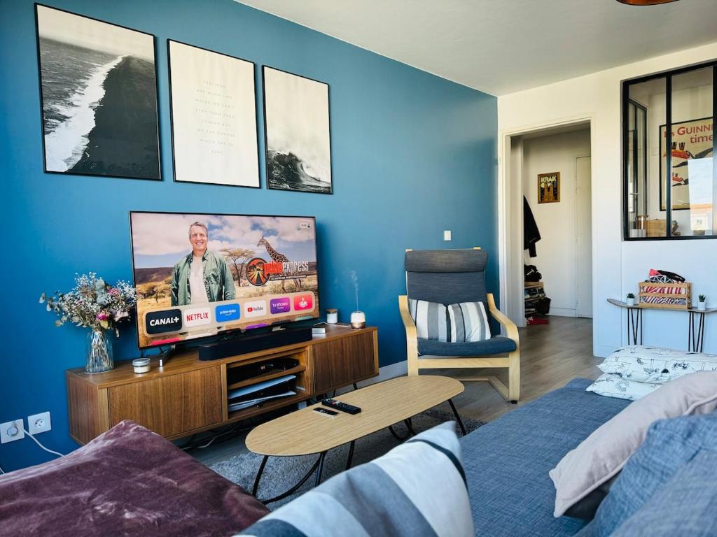 Il comprend un salon doté d'une télévision et d'un mur bleu. dans l'établissement Appartement Bordeaux avec parking privé, à Bordeaux