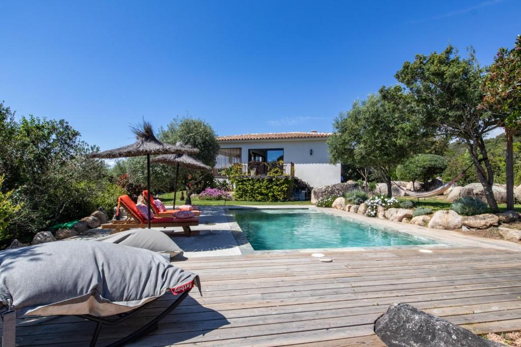 une femme assise sur une chaise à côté d'une piscine dans l'établissement Villa MARE E MACCHIA, à Lecci