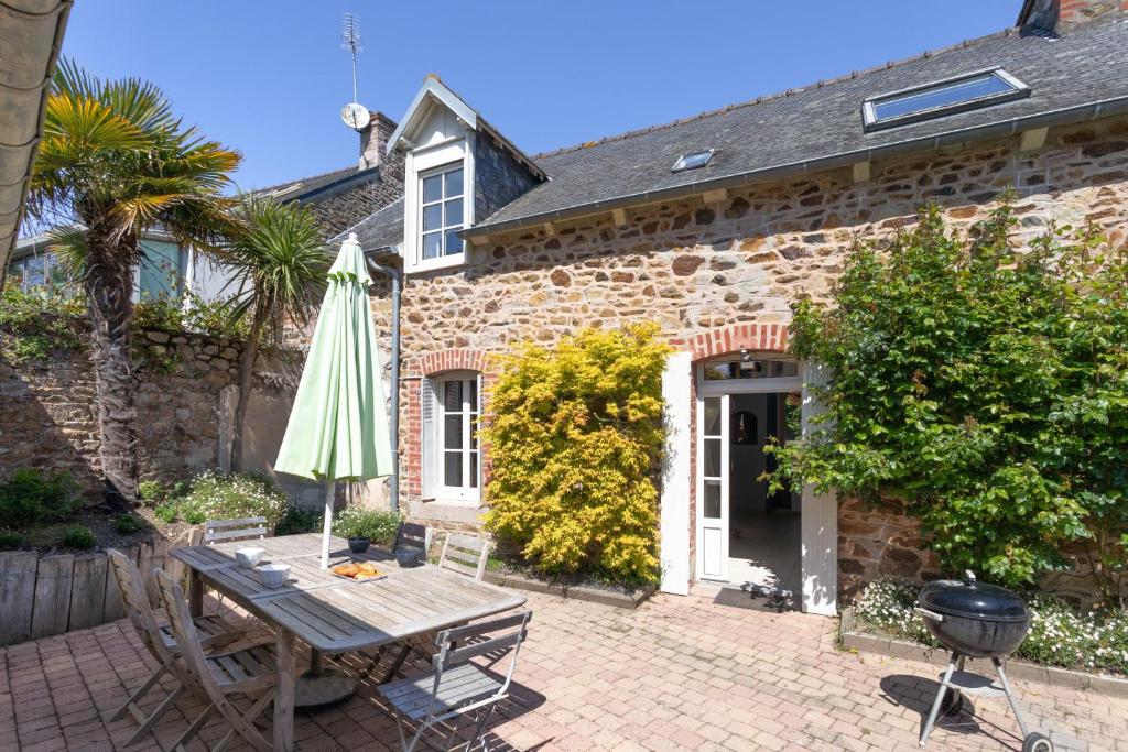 une maison en briques avec une table, un parasol et un barbecue dans l'établissement Ker Aventin - Jolie maison classée 3 étoiles, à Pléneuf-Val-André