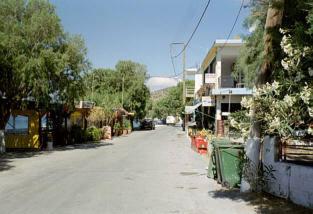 an empty street in a town with buildings and trees at Xenos Apartments in Keratokampos