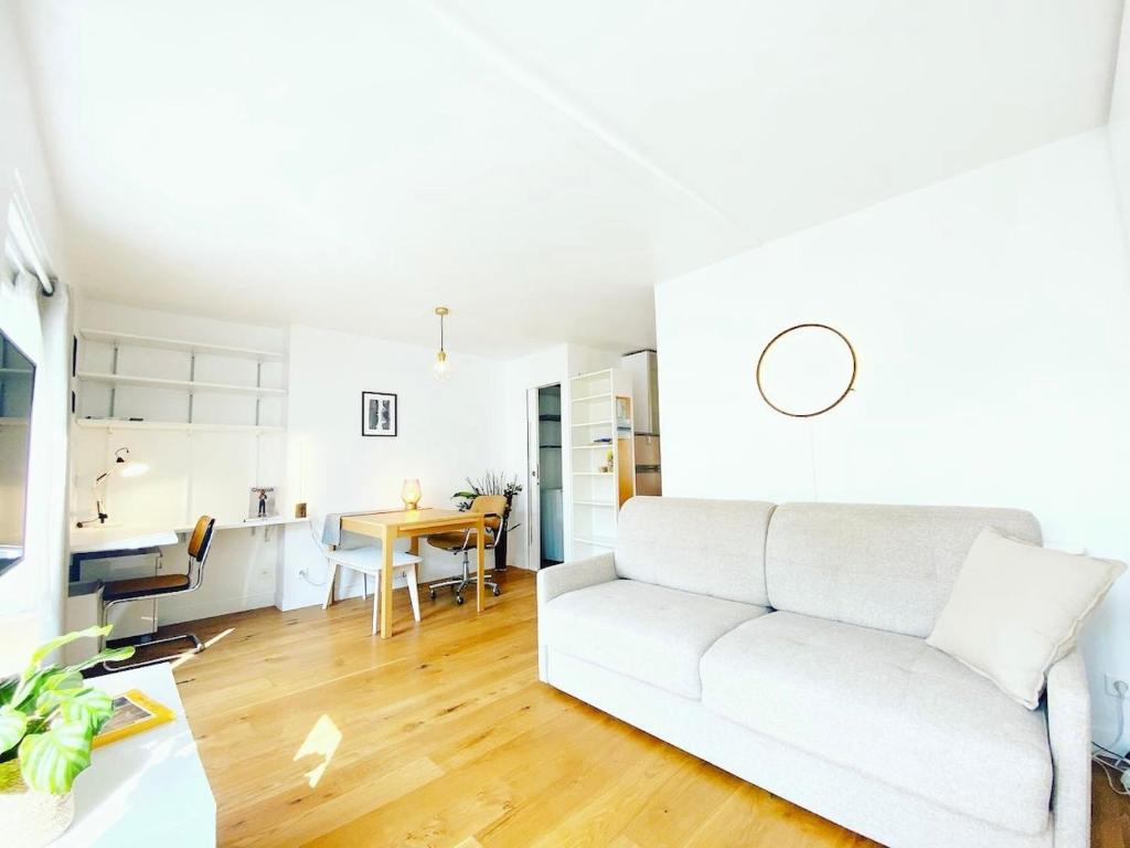 un salon avec un canapé blanc et une table dans l'établissement Au calme sur jardin tres bel appartement lumineux, à Paris