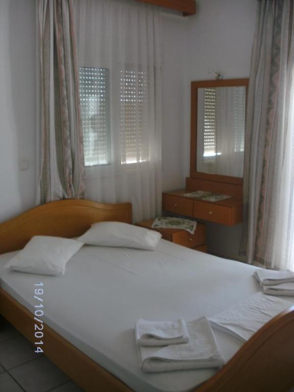 a bedroom with a white bed and a mirror at Xenos Apartments in Keratokampos