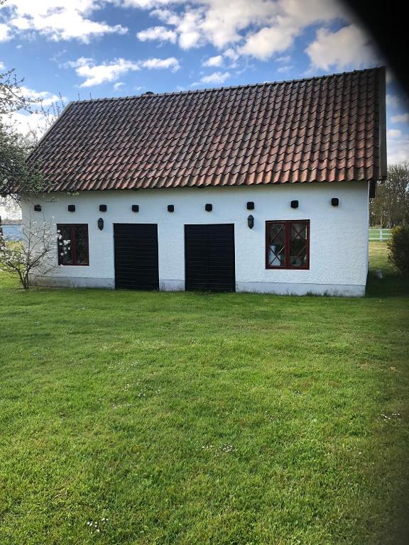 a white building with four doors on a grass field at Lilla Baren i Träkumla in Visby