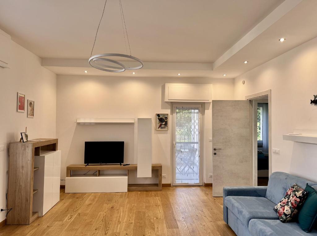 a living room with a blue couch and a tv at Verdeacqua my villa in the pinewood in Spotorno