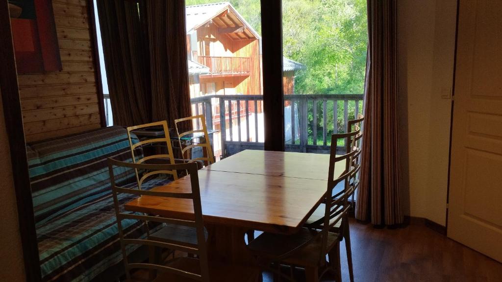 un tavolo in legno con sedie in una stanza con una grande finestra di Hameau 4 106 - SPA & PISCINE appartement 6 pers a Orelle