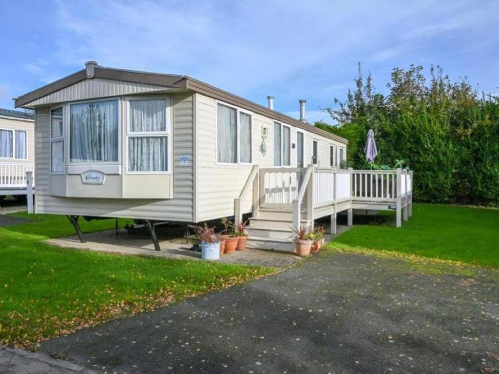 a tiny house with a porch and a deck at Charming Caravan To Hire At Breydon Water Holiday Park In Norfolk Ref 10003Tc in Belton