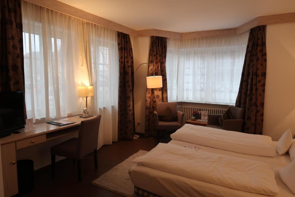 a hotel room with two beds and a desk at Hotel-Restaurant & Metzgerei Rößle in Dettingen an der Erms