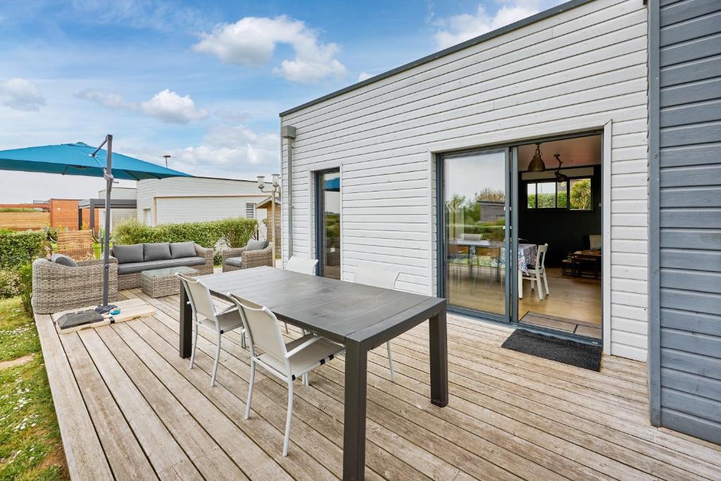une terrasse en bois avec une table et des chaises. dans l'établissement La Côte des îles - à 600m de la plage, à Les Moitiers-dʼAllonne