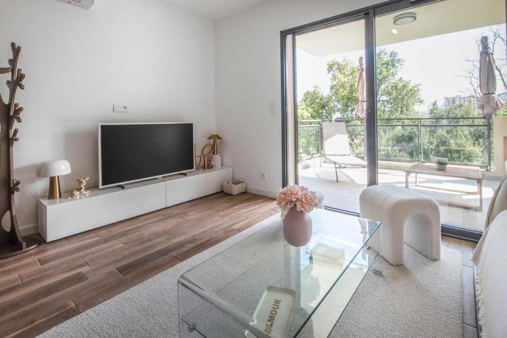 un salon avec une télévision et une table en verre dans l'établissement Appartement T3 de charme avec Terrasse - Hauteurs Bastia, à Bastia