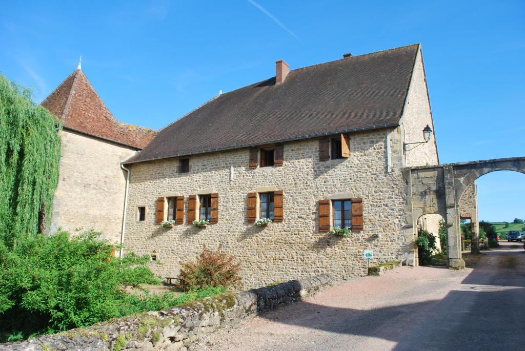 a stone building with a black roof and a bridge at Chambre D' Hotes Des Collines in Amanzé