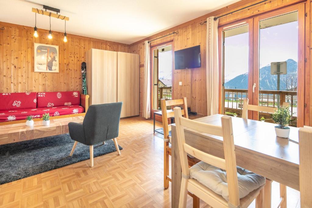 ein Wohnzimmer mit einem Tisch und einer roten Couch in der Unterkunft NOEMA - vue montagne in La Toussuire